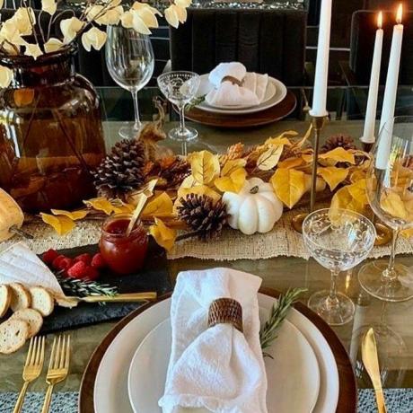 Décor de table à manger rustique avec des pommes de pin et des feuilles d'automne