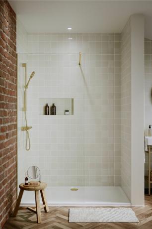 cabina doccia con piastrelle quadrate crema, pavimento a spina di pesce, sgabello in legno, muro di mattoni a vista