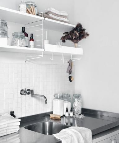 weißes Metallbandsystem über einer Edelstahl-Arbeitsplatte und einem Waschbecken in einem Wasch-/Hauswirtschaftsraum