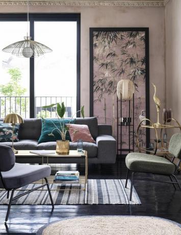 sala de estar rosa con sofá y silla grises, piso negro, mesa de café dorada, carrito de bar, lámpara colgante, alfombra de rayas