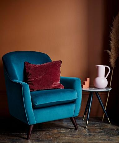 sillón de terciopelo azul y pared de terracota