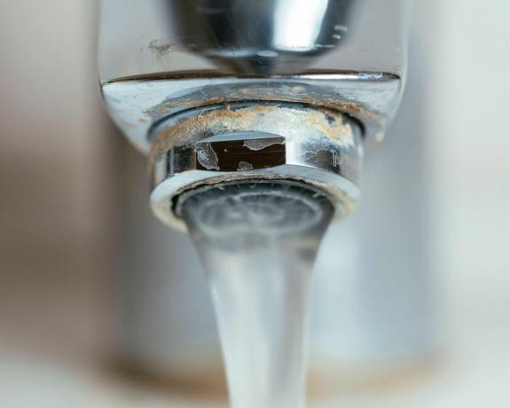Schiuma di sapone e accumulo di calcio su un rubinetto causato da acqua dura