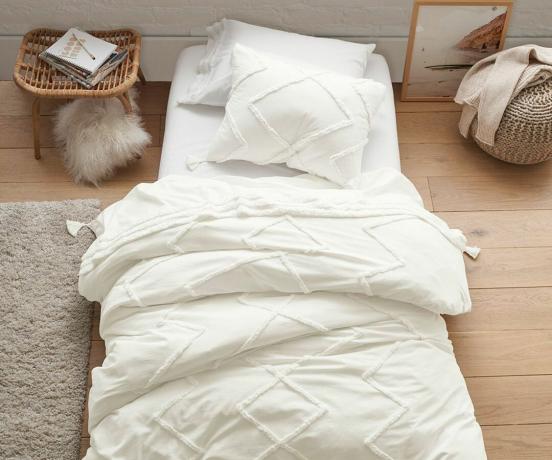 Camera da letto minimalista con biancheria da letto bianca e piccoli accenti