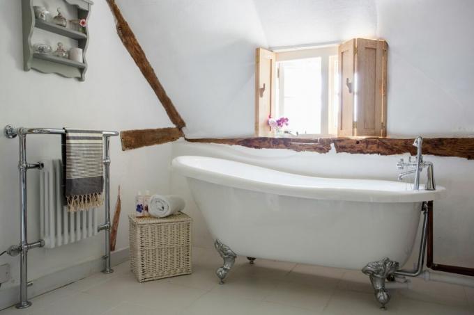 ванна на ножках в коттедже с соломенной крышей и балками, внесенным в список памятников архитектуры