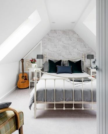 Ett gäst sovrum på ett ombyggt loft med ett vitt och grått färgschema