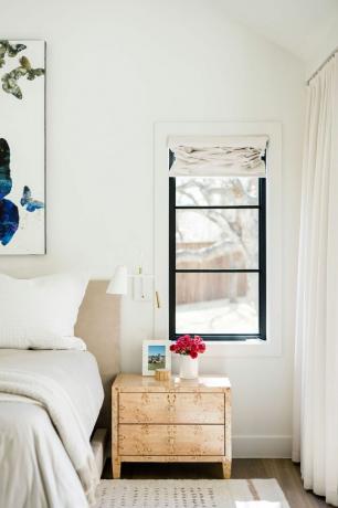 Ein helles Schlafzimmer mit Wandleuchte über dem Nachttisch