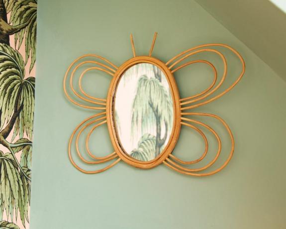 Rotangpalmas tauriņu spogulis uz zaļo sienu dekoru, ko izstrādājis Sass & Belle