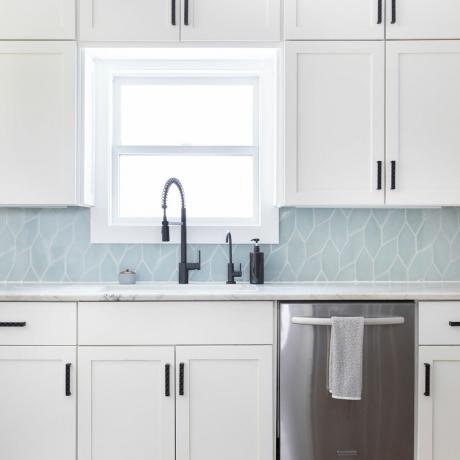 Blaue, modern geflieste Rückwand in einer modernen Küche mit weiß glänzenden Schränken