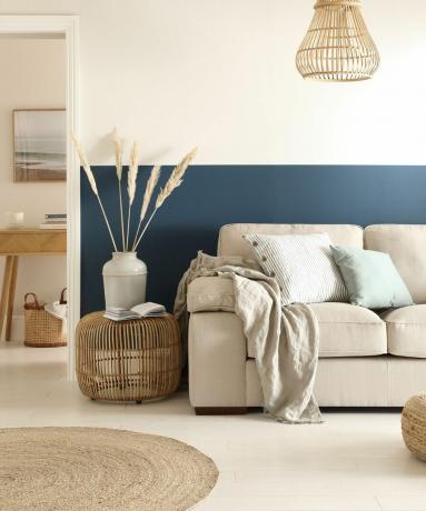 Ruang tamu berwarna krem ​​​​dan biru dengan sofa krem ​​​​dan permadani goni