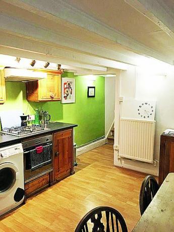 Pirms virtuves attēla, kurā redzamas tumšas koka detaļas, granīta darba virsma un laima zaļi krāsotas sienas
