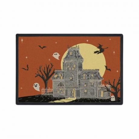 Un preș de Halloween cu o ilustrație a unei case bântuite