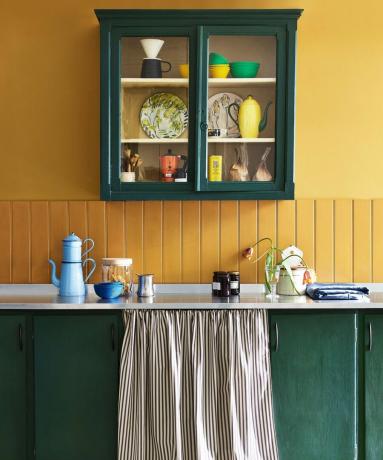 Eine gelbe Küche mit grüner Spüle und Schrank