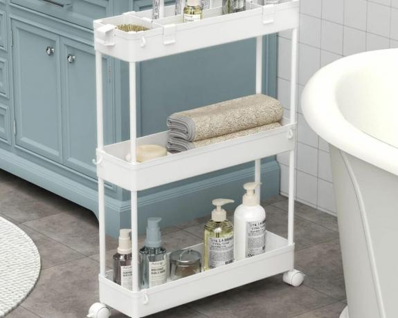 白い浴槽の隣にある白いユーティリティカートと、狭いスペースにある青い洗面化粧台