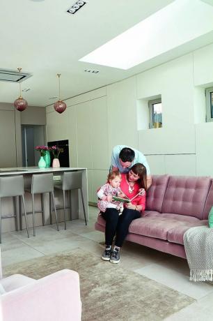 atvērta plānojuma virtuves ēdamistaba un viesistabas zona ar rozā dīvānu