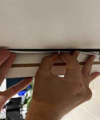 Kézzel rögzíti a drótot a szekrény aljához