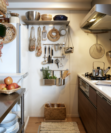 Una parete in una piccola cucina con varie soluzioni di stoccaggio per appendere pentole, padelle, utensili da cucina e altro