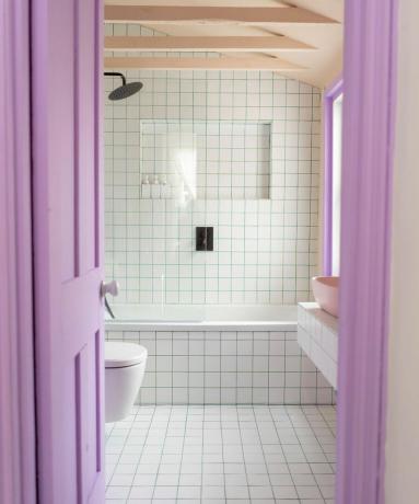 Piccolo bagno piastrellato bianco con tende viola