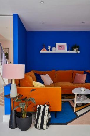 Un soggiorno con decori dipinti a parete blu e divani in velluto arancione