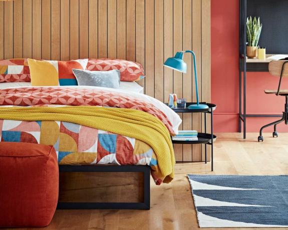 miegamasis su pagalvėlėmis ant lovos, medinėmis dailylentėmis ir šiuolaikišku apšvietimu – buveinė