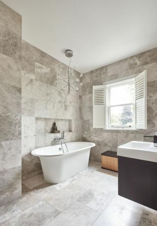 vannas istaba ar lielformāta flīzēm, brīvi stāvoša vanna un lustra