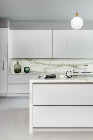 cocina blanca contemporánea con placa para salpicaduras de mármol e isla, gabinetes blancos