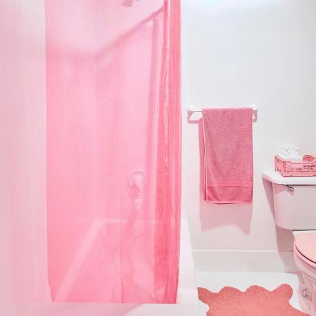 Vonios kambarys su rožiniu rankšluosčiu, dušo užuolaida ir vonios kilimėliu