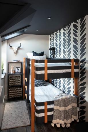 Cameră pentru copii cu paturi supraetajate negre și din lemn de tec, tavan vopsit în negru, pereți albi și tapet cu model monocrom