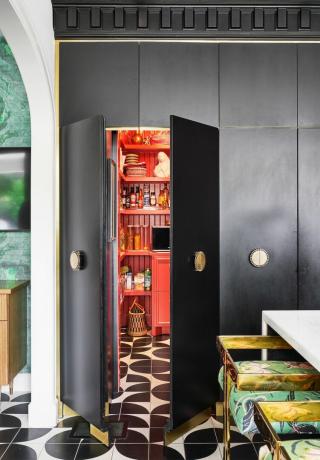 värikäs keittiö kuvioin, mustavalkoinen lattia, mustat kaapistot ja punainen ruokakomero