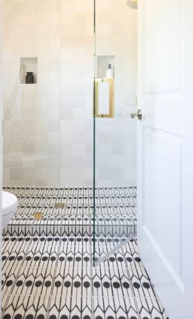 대담한 그래픽 흑백 바닥 타일, 유리 샤워 문, 정사각형 타일 벽이 있는 샤워실