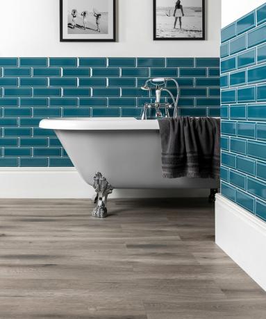 Azulejos azul-petróleo no banheiro com banheira branca e piso cinza da Flooring Mountain