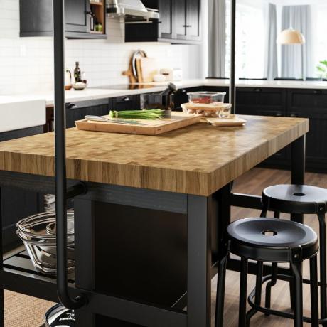 Zwarte keukenkrukken rond houten aanrechtbladen van het keukeneiland in kleine ruimte