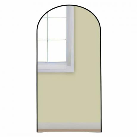 Črno obokano ogledalo, ki odseva okno in rumeno steno