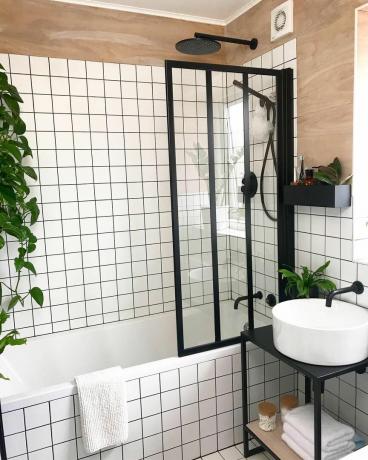 Banheiro com ladrilhos de grade branca e tela de chuveiro estilo Crittal