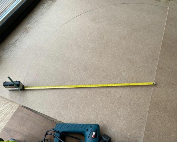 Målebånd forlænget over mdf-ark på gulvet