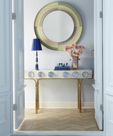 Uma ideia de espelho redondo no corredor em tons pastel por Jonathan Adler com decoração em pintura de parede em azul pastel