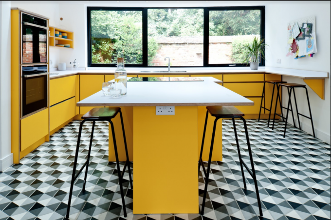 armoires de cuisine jaunes avec sol à motifs et îlot de cuisine jaune