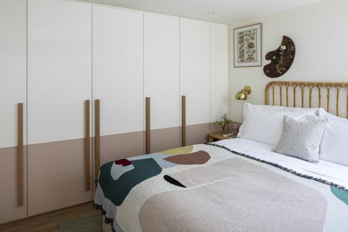 camera da letto color pastello con coperta a motivi geometrici, letto in rattan, decorazioni murali, armadi