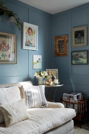 sinised seinad elutoas koos kunstiteostega padjadega diivani kõrval