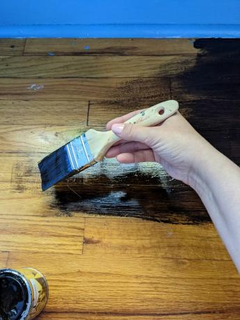 Mancha de gel de pintura a mano sobre un piso de madera con pincel