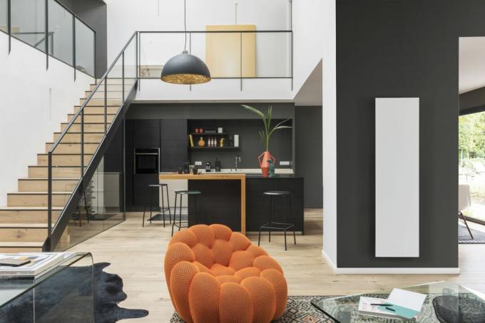 Schwarz-weiße Küche im offenen Wohnbereich, moderne Treppe, schwarzer Handlauf, Holzboden