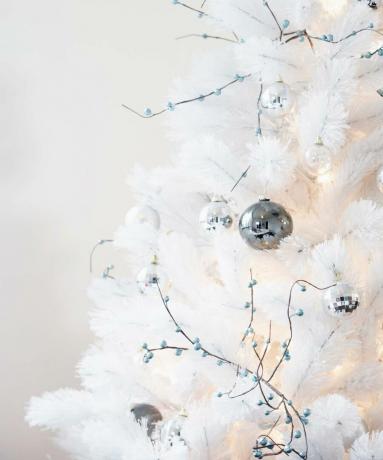 weiße Weihnachtsbaumzweige mit metallischen Ornamenten