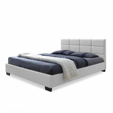 Un letto imbottito bianco con lenzuola blu