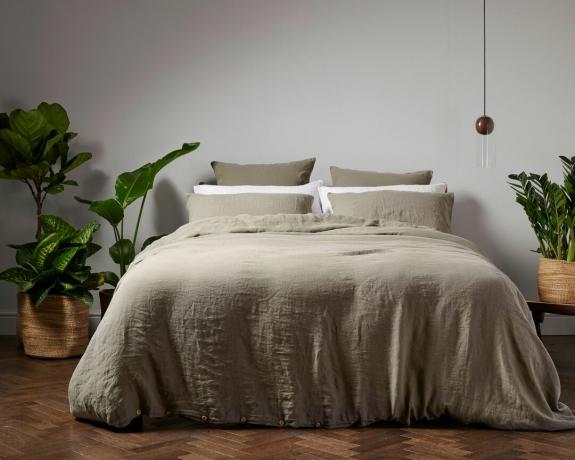dobbeltseng opredt med linned sengetøj i roligt soveværelse