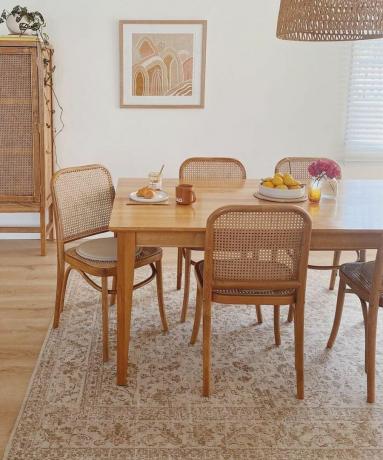 Ein beiger Essbereich mit Holzstühlen, einem Esstisch und einem Teppich