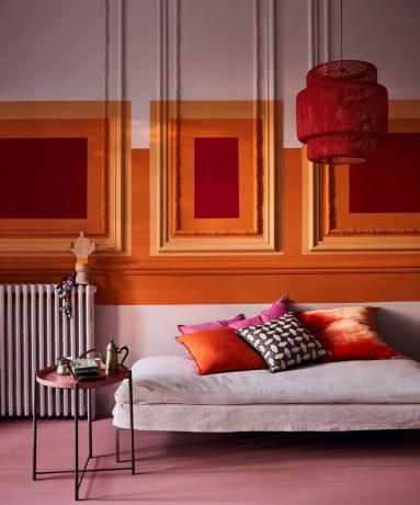 Ett djärvt vardagsrum med rosa, orange och röd väggdekor med kritafärg av Annie Sloan i nyanserna Antoinette, Barcelona Orange och Emperor's Silk