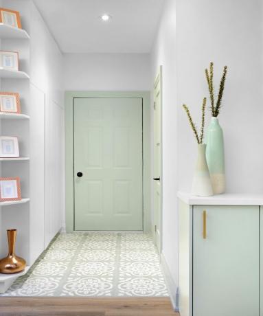 小さなキャビネットとタイル張りの床の白い玄関の端にあるミントグリーンの正面玄関
