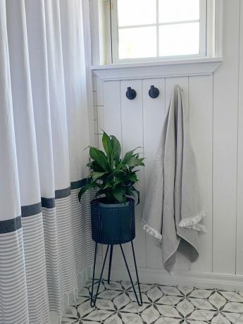 Baltas svečių vonios kambarys su sienų dailylentėmis ir atitinkamais juodais veidrodžiais