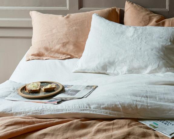 lin sengetøy i muskat på en seng med frokost på et brett - brød