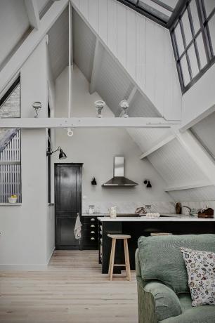 Cucina a pianta aperta in un loft convertito con soffitti alti, pareti bianche, armadi blu scuro