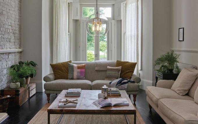 sala de estar neutra com dois sofás e uma grande mesa de centro quadrada, janela tipo bay window